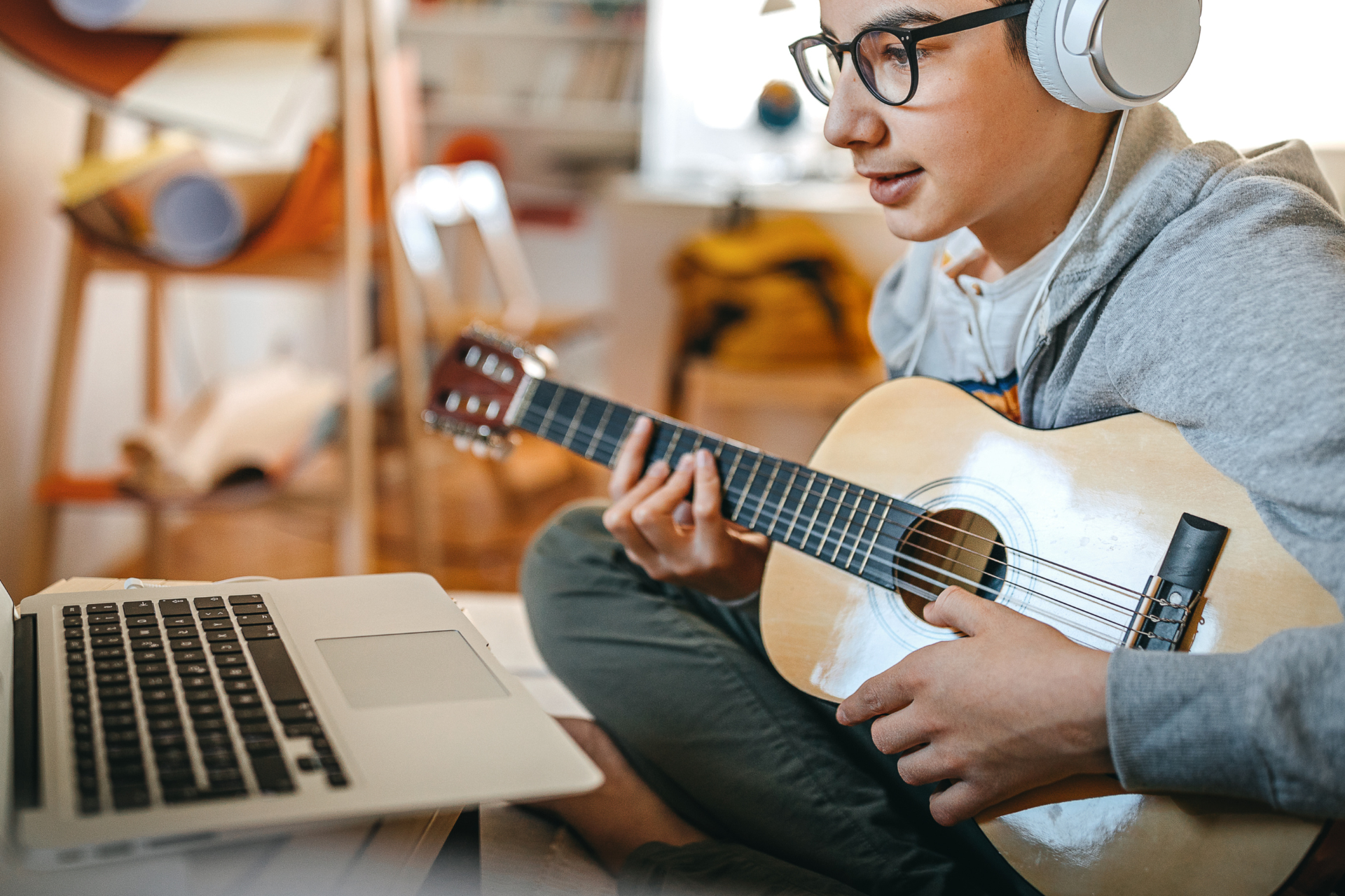 Jak wybrać gitarę dla dziecka? Chłopak gra na gitarze podczas lekcji online.